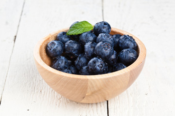 Blueberries in a small wooden bowl on a painted table