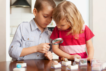 Children are considering a magnifying glass collection of stones