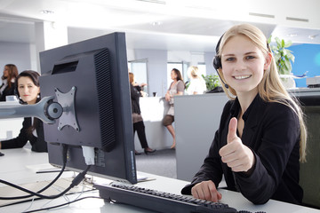 Callcenter Mitarbeiterin lächelt mit Daumen hoch Porträt