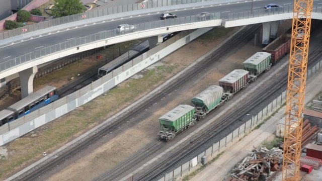 railroad cargo train and cars moving on bridge in city