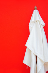 white sunshade leaning against glaring red wall