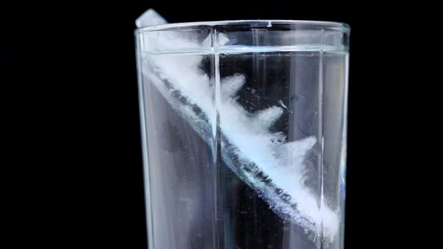 close-up shot of glass with water and ice rotating on black