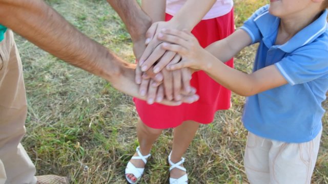 family of three people makes pile of hands outdoor