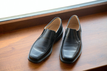 man's shoes stand on a window sill