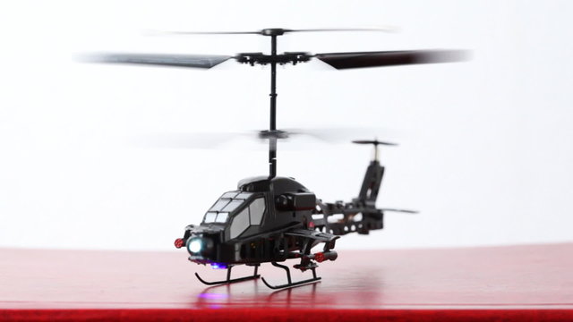 toy helicopter is on table,  then flies up upwards