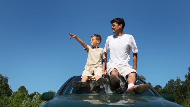 father and son sitting on roof of car and talking, part2