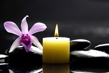 aromatherapy candle and pink orchid on zen stones
