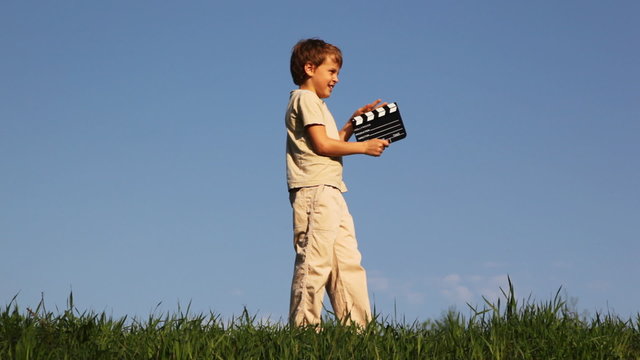 Boy comes on grass, click clapperboard