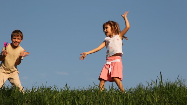 Boy shakes rattle in form of hands, and his sister dances