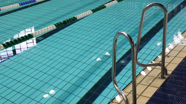 swimming pool with clear blue water, and rail at its edge
