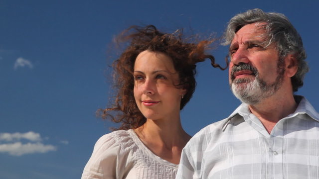 senior and adult daughter stand in profile against sky
