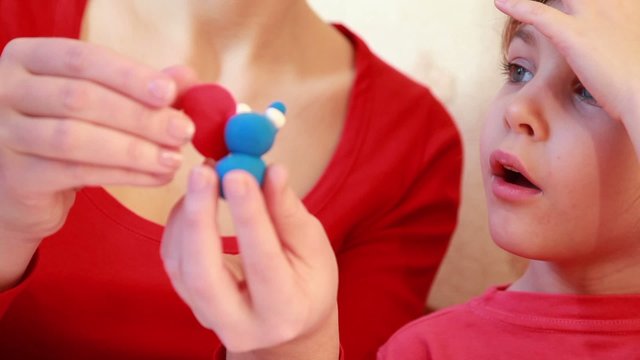 Woman sculpt from plasticine, girl  watch with interest
