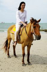 young woman riding a horse on the beach