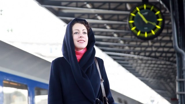 woman at the train station waiting and looks at watch