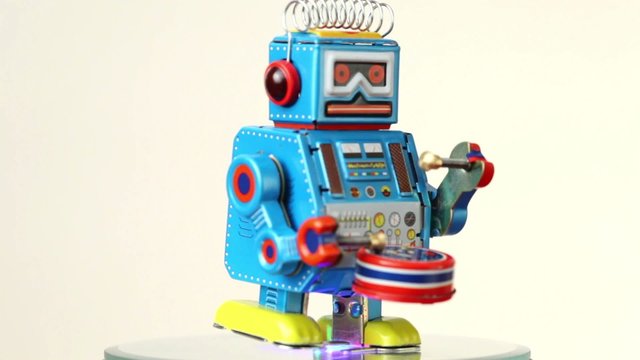 closeup of clockwork robot walks on table, beats drum