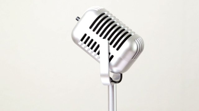 closeup metallic microphone rotates on white backdrop