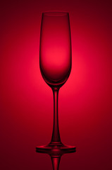 Empty champagne glass on red background