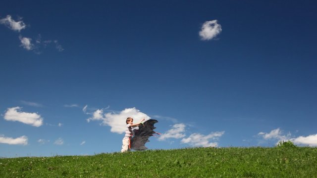 boy launch black kite on field against sky with cloud