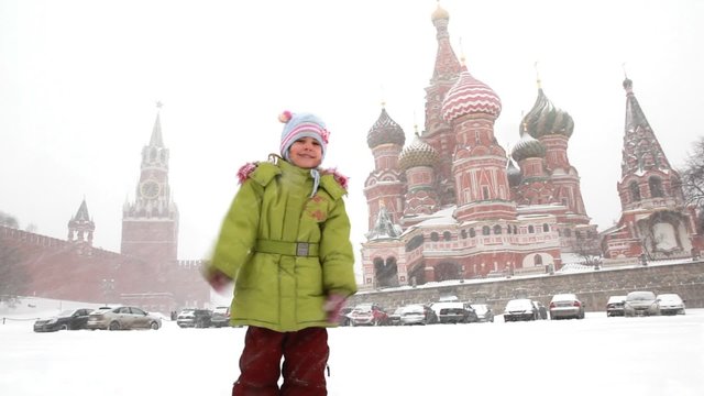 girl plays with snowballs near Moscow Kremlin under snowfall