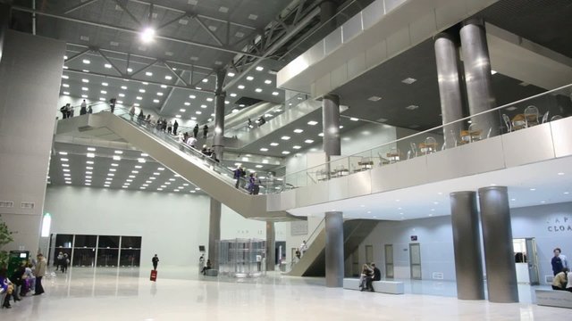 business center with visitors, escalators move between them.