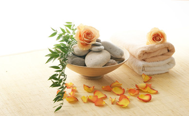 A spa composition of salt, towels and stones on a bamboo mat