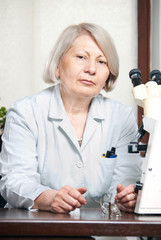 Female doctor looking in office with microscope