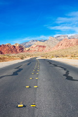 Asphalt Highway Disappearing into Desert Mountains