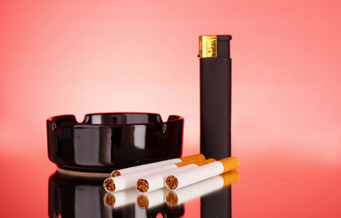 Fototapeta premium Cigarettes, ashtray and lighter on red background