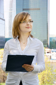 Young Business Woman With Clipboard On Building Background