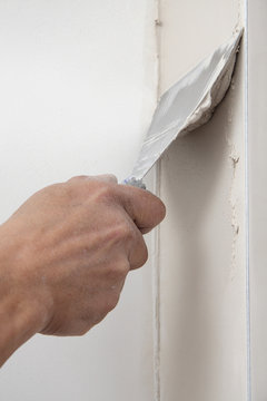 main posant enduit de lissage sur mur