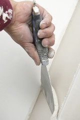 main posant enduit de lissage sur mur