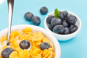 bowl of cornflakes with milk and blueberries