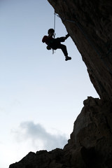 Silhouette of rock climber against sky background