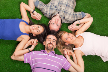 Young People Lying on Green Ground with Hands Joined