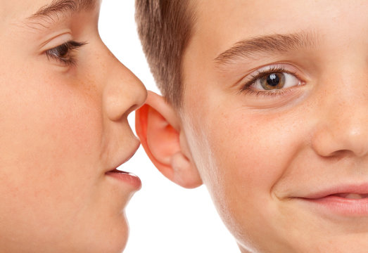 Zwei Jungen flüstern sich Neuigkeiten ins Ohr