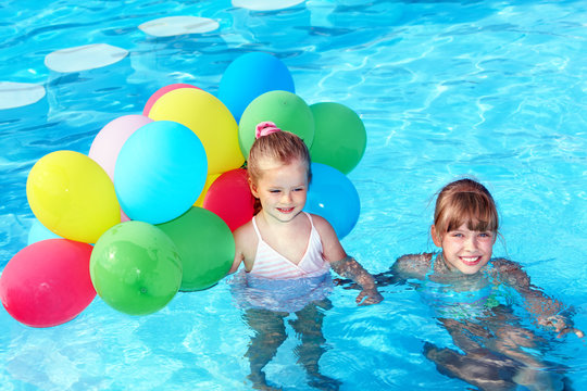 Children playing with balloons in swimming pool.