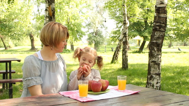 mother and daughter eat and drink in park