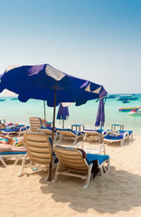 Two sun beds for sunbathing with a blue umbrella on the beach