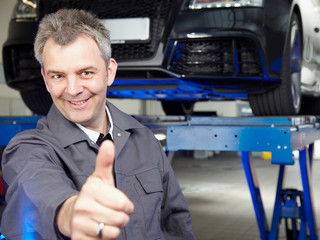 Master mechanic in a garage shows thump up