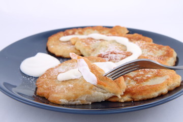 Potato pan cakes with cream and sugar being eaten with a fork