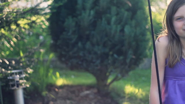 Preteen girl swinging and smiling