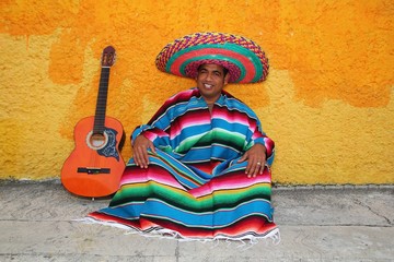Happy mexican man sitting with a guitar