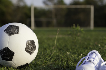 Футбольный мяч и детские белые кеды на футбольном поле