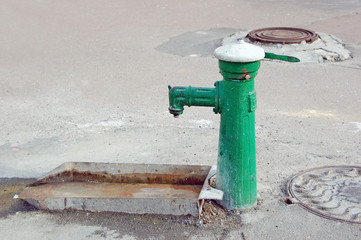An old fashioned water pump above a rusty trough