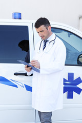 young doctor writing in front of ambulance