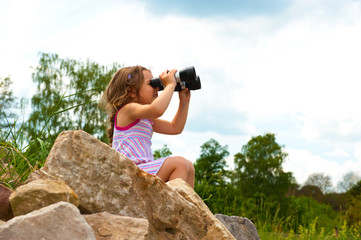Kind mit dem Fernglas auf dem Felsen