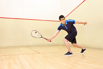 Squash player hiting a ball in a squash court