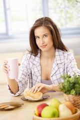 Obraz na płótnie Canvas Smiling woman eating breakfast