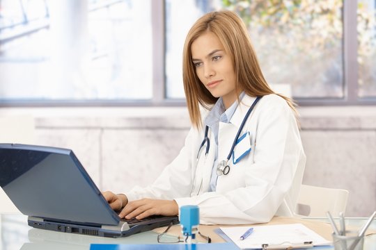 Young doctor busy in office using laptop