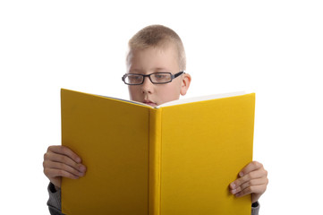boy with glasses reading a big yellow book